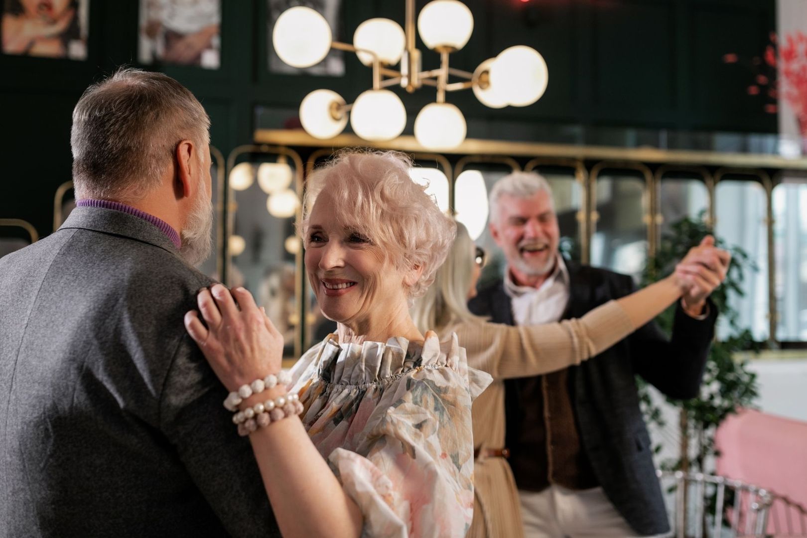 Ældre voksne danser smilende sammen i en lys dansesal