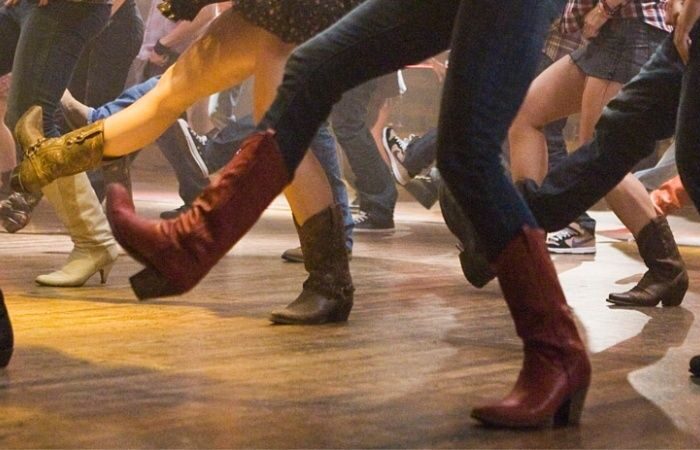 Gruppe dansere øver synkrone trin på dansegulvet iført støvler
