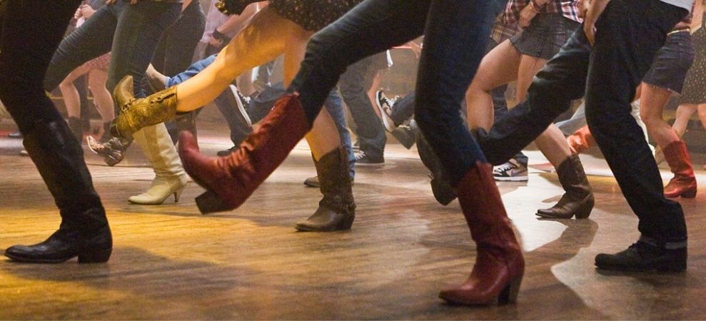 Gruppe dansere øver synkrone trin på dansegulvet iført støvler